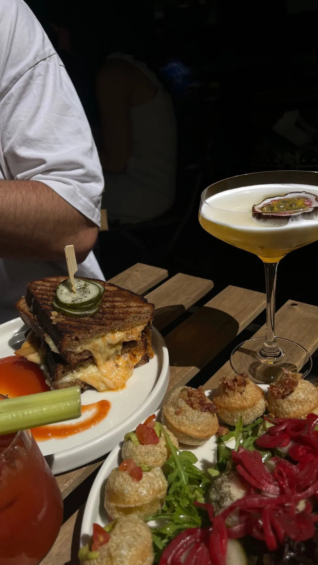 Plate with grilled sandwich, pani puri and cocktails at the bar