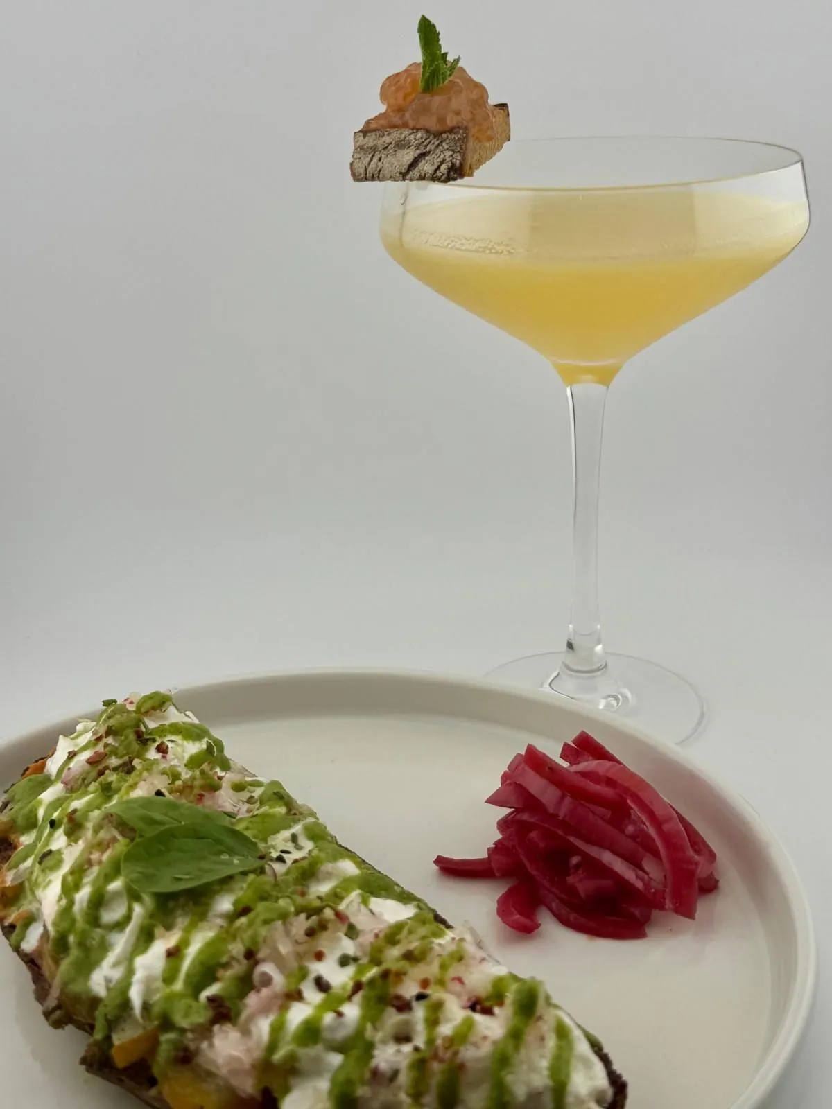 Burrata-Stulle mit Zucchini-Basilikum-Creme und Radieschen, daneben ein Breakfast Martini