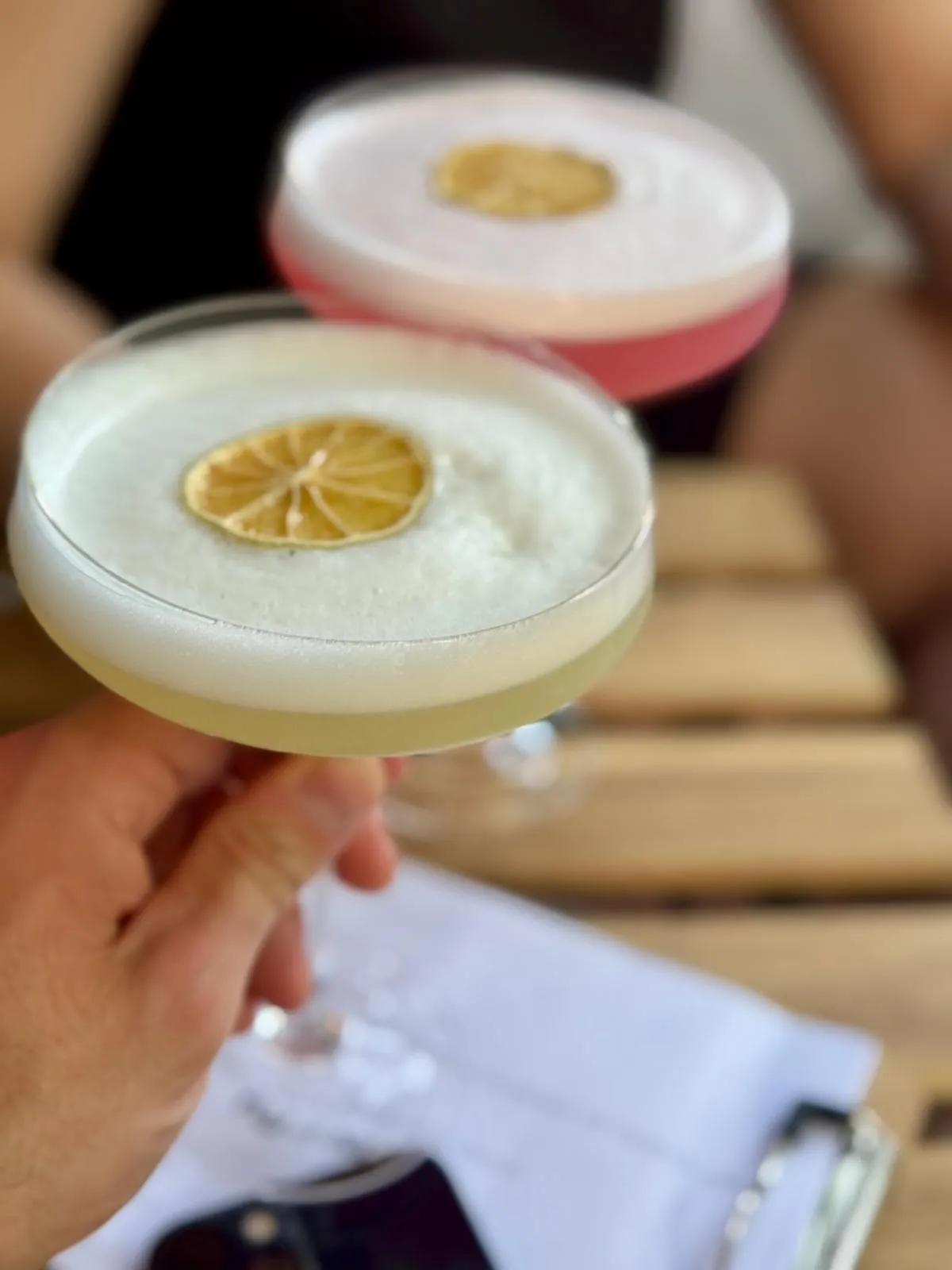 Zwei Sours mit Zitronenscheibe, einer in der Hand