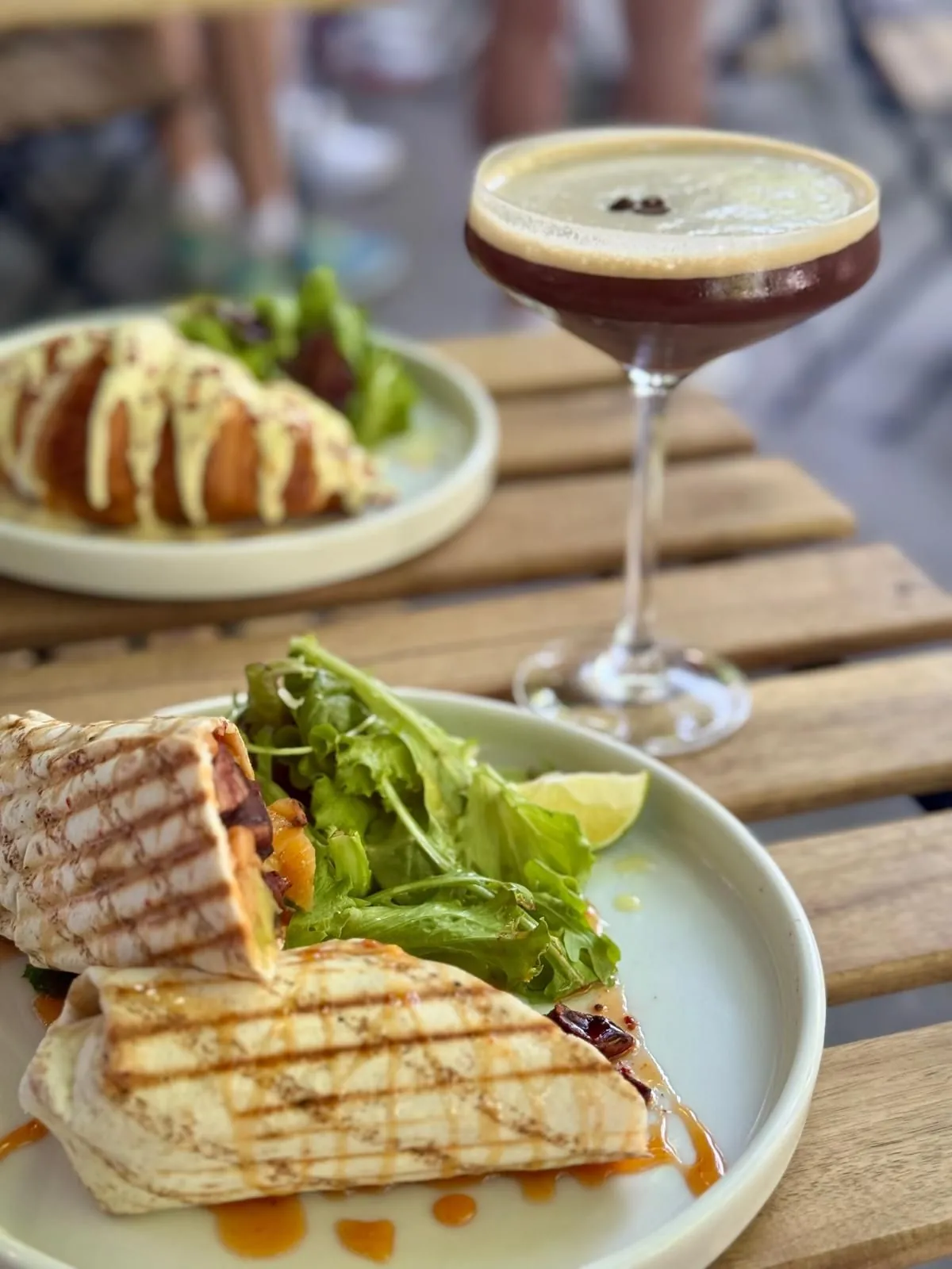 Eggs Benedict Croissant und Burrito auf der Terrasse, daneben ein Espresso Martini