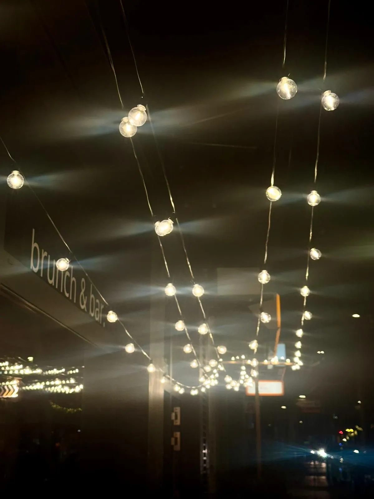 Lichterketten hinter der Fensterfront von butter.fly bei Nacht