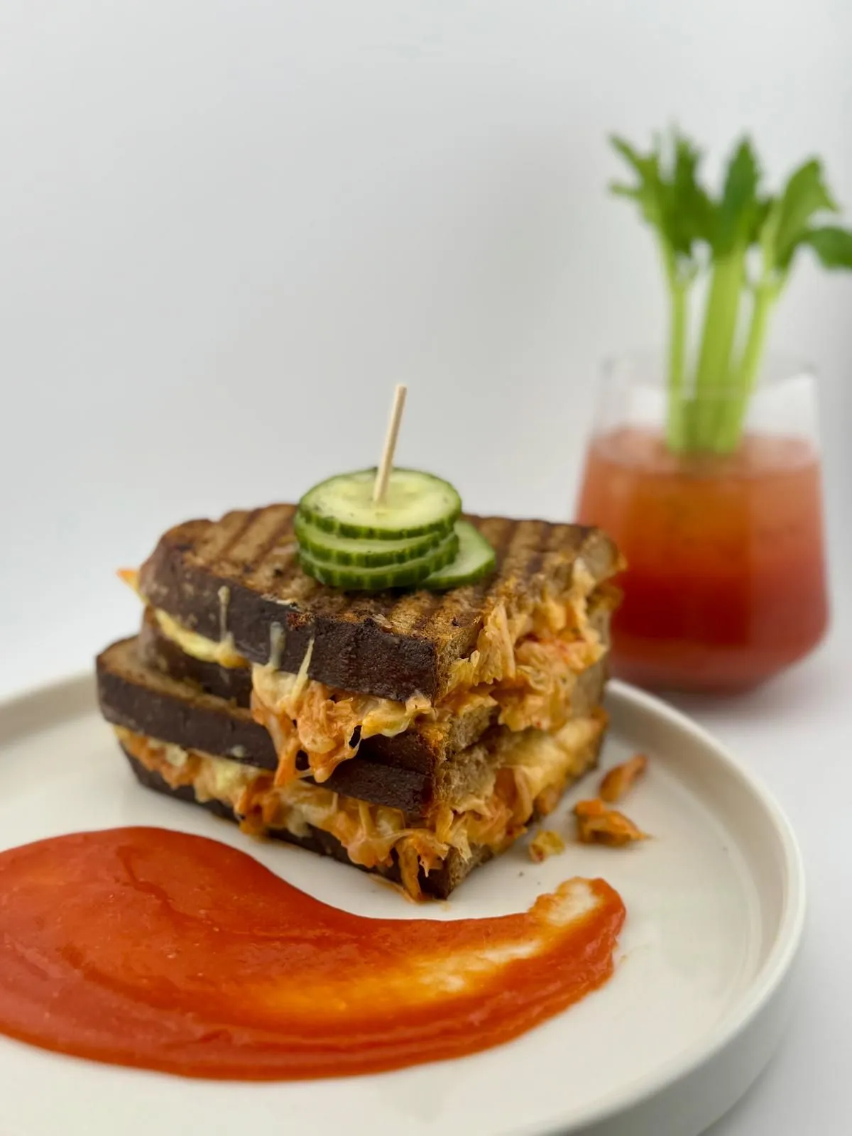 Grilled Sandwich mit Kimchi und Tomaten-Marmelade, daneben eine Bloody Kraut Mary mit Sellerie
