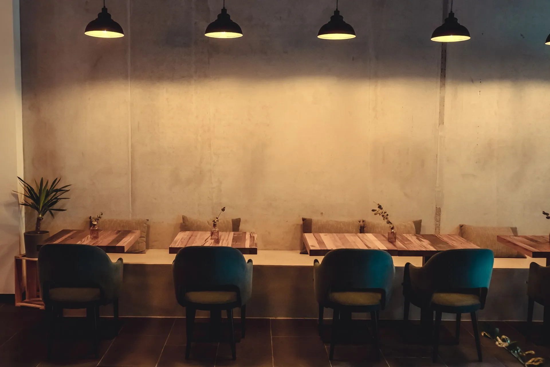 butter.fly dining room: concrete wall, pendant lamps, wooden tables and blue chairs